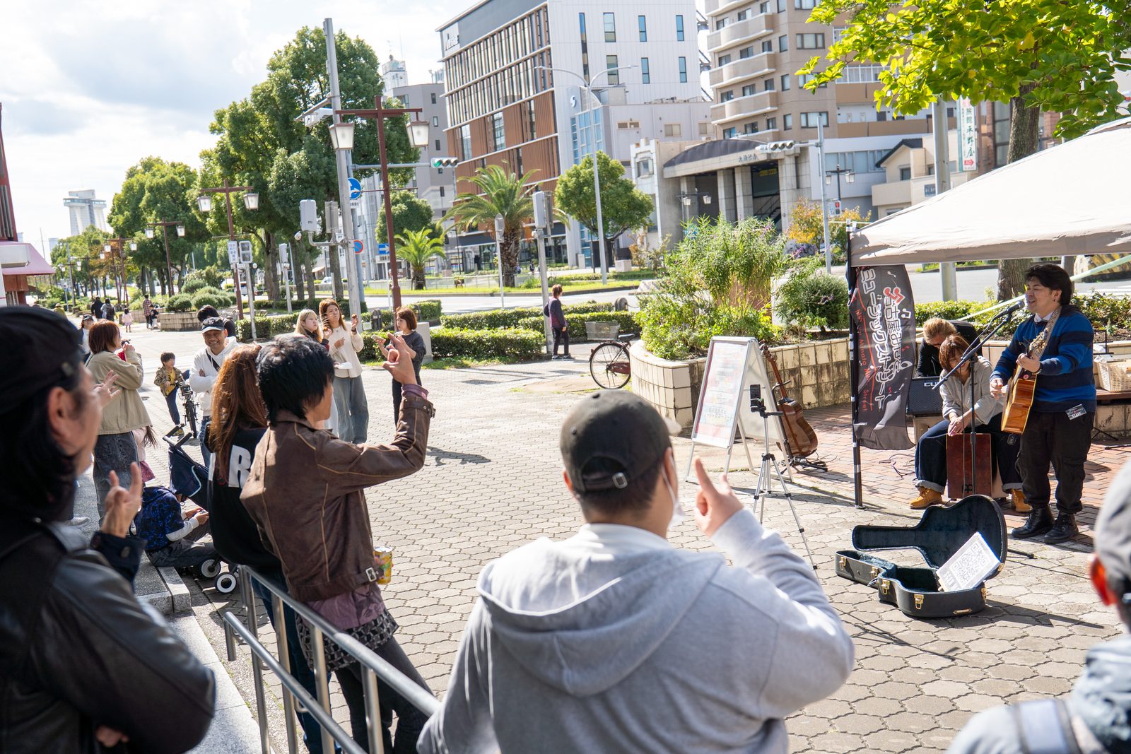 江川線沿いの歩道での演奏と、足を止めて聴く人たち（前回の様子）