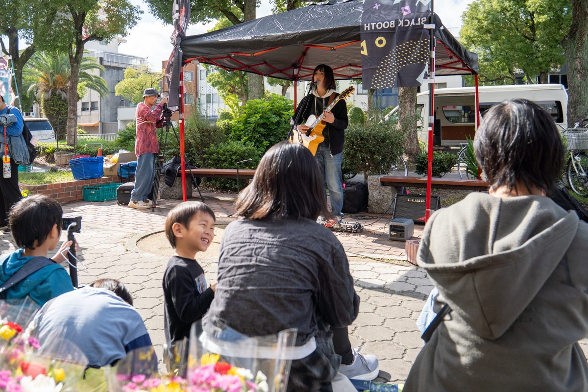ブースのテントで演奏する出演者と観客